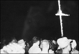 A group of people watching a cross burn. Photo courtesy of the National Archives.